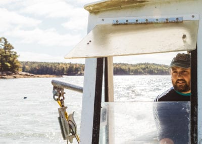 Winnegance Oyster farmer driving boat on New Meadows River in Maine